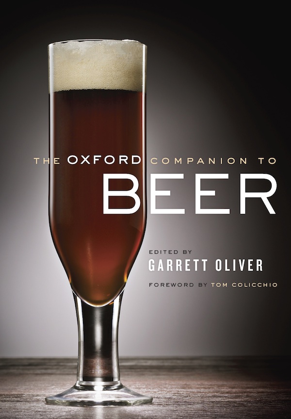 The Oxford Companion to Beer book cover featuring a dark amber beer in a pilsner glass, edited by Garrett Oliver with...