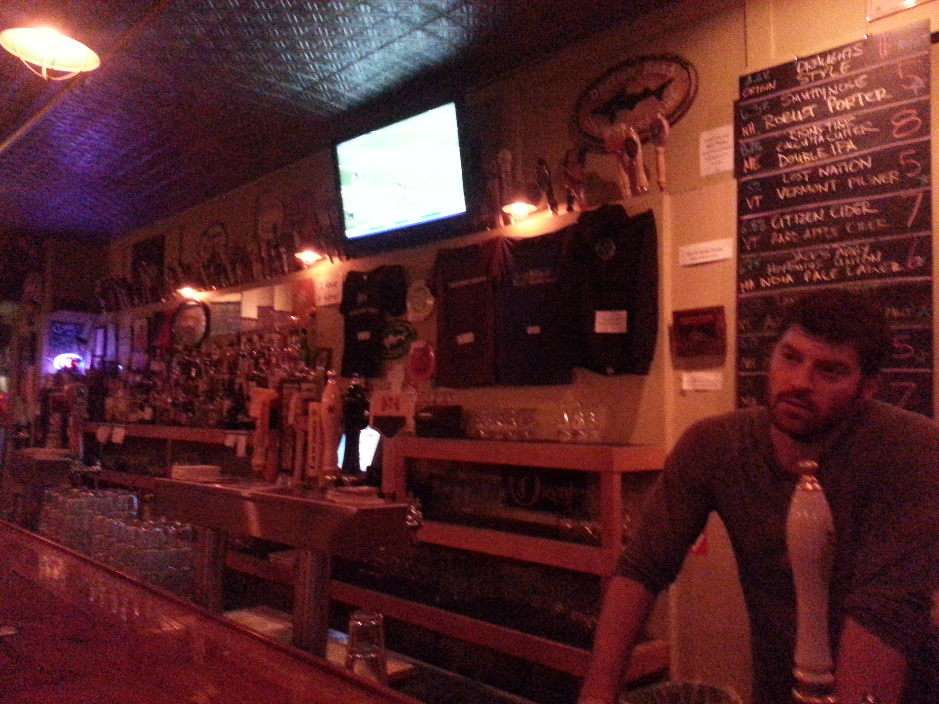 Interior of Three Penny bar in Montpelier, Vermont, with patrons at counter and craft beer list on wall, circa 2013
